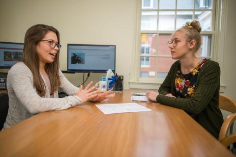 Student sitting at desk speaking with an academic advisor 